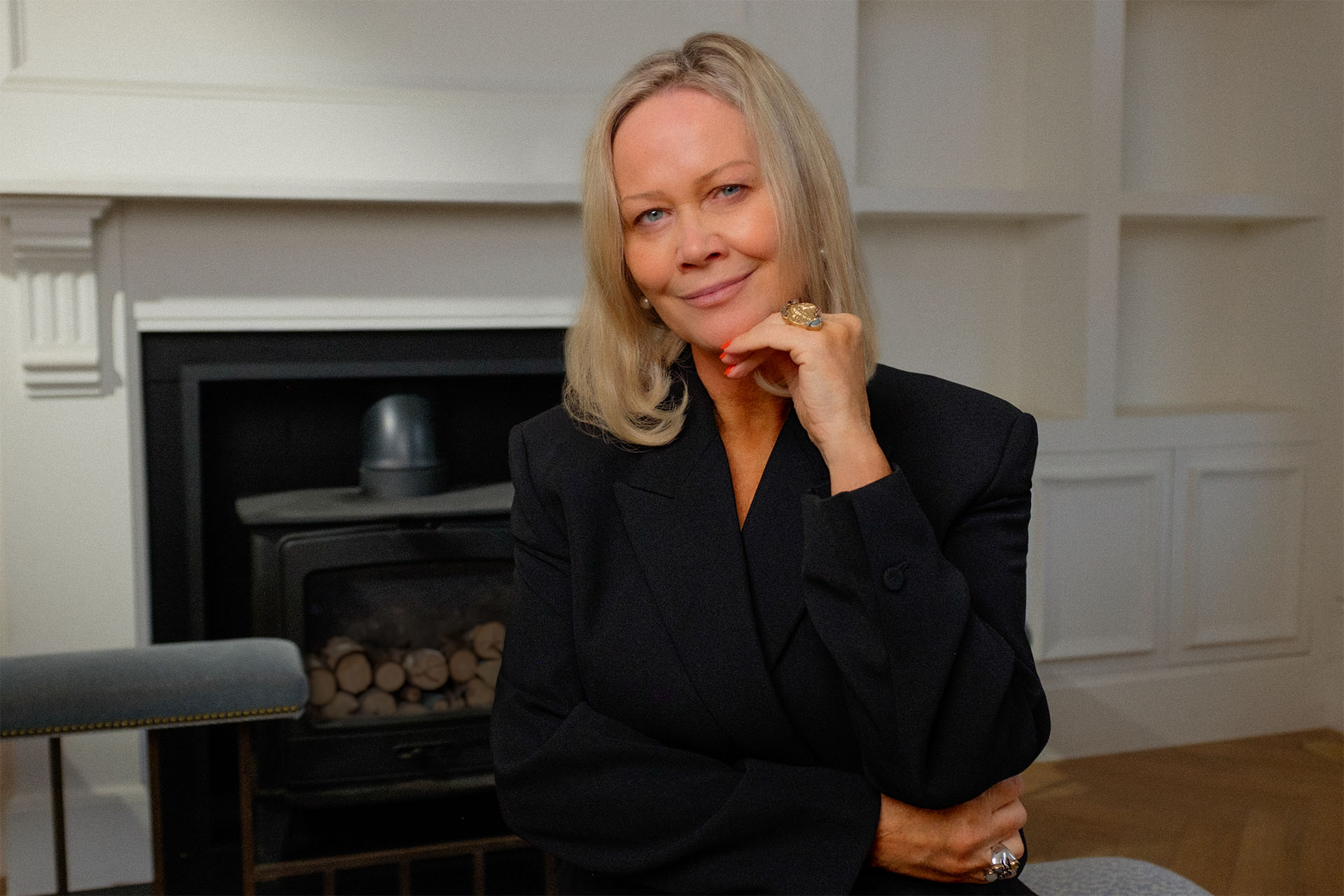 Katy Sayburn dressed elegant by the chimney in her apartment.